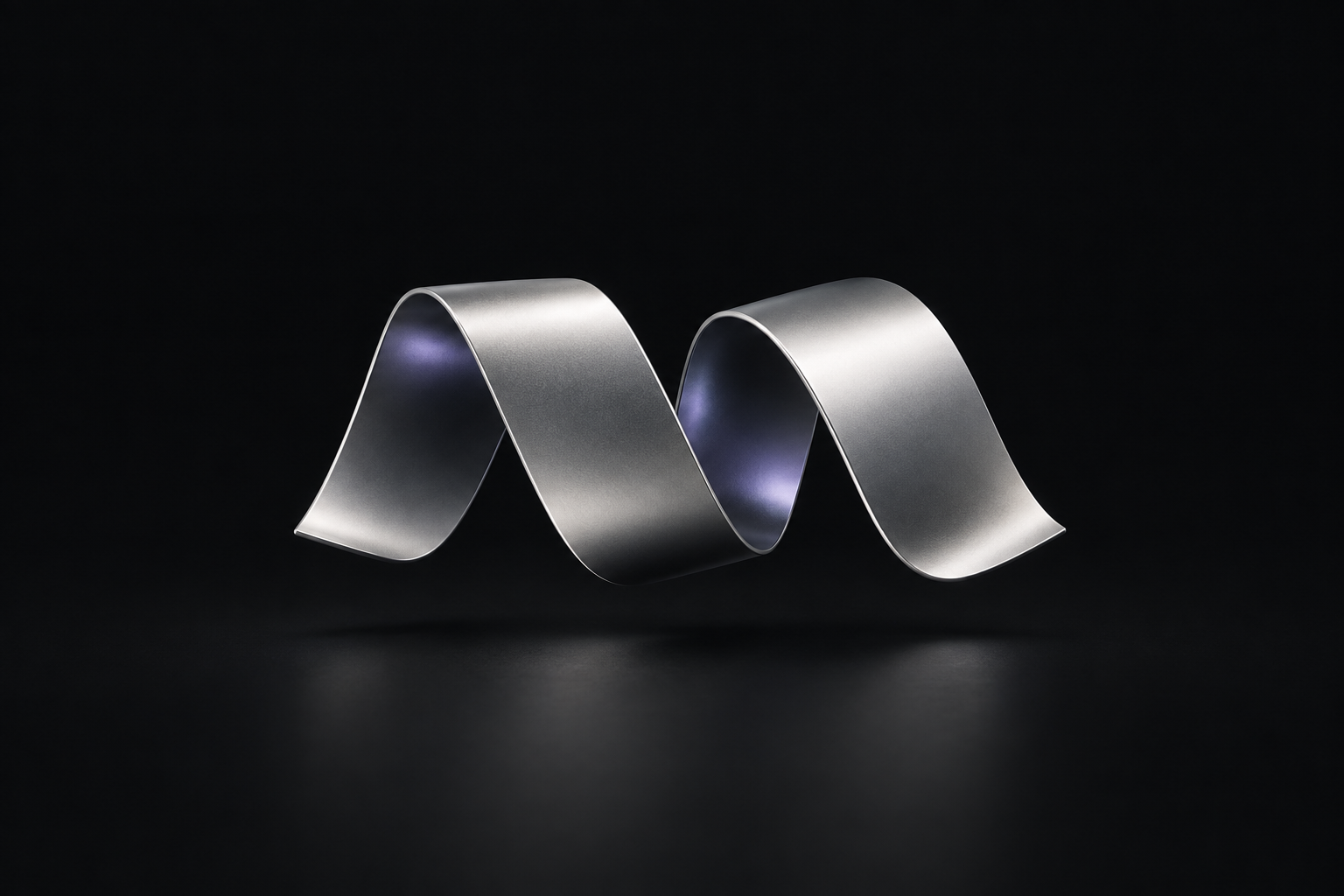 A silver ribbon sculpture on charcoal, with two open folds suggesting ideas taking shape.