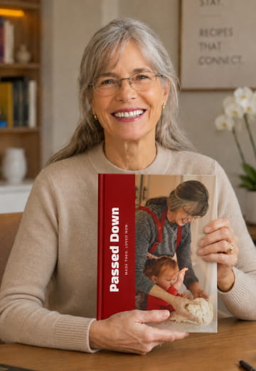 Woman holding a red Passed Down cookbook at a table
